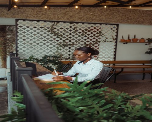 A professional woman smiling while taking a micro break at her bright office desk near green plants