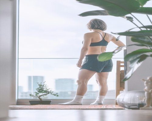 A person stretching their arms gently while standing in a brightly lit modern apartment