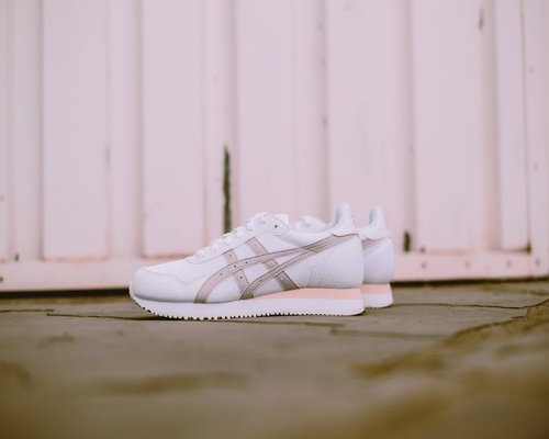 A pair of clean supportive walking shoes sitting beside an urban apartment door