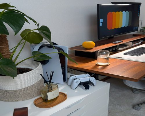A clean workspace at home featuring an external monitor, notebook, and a glass of water on a wooden desk